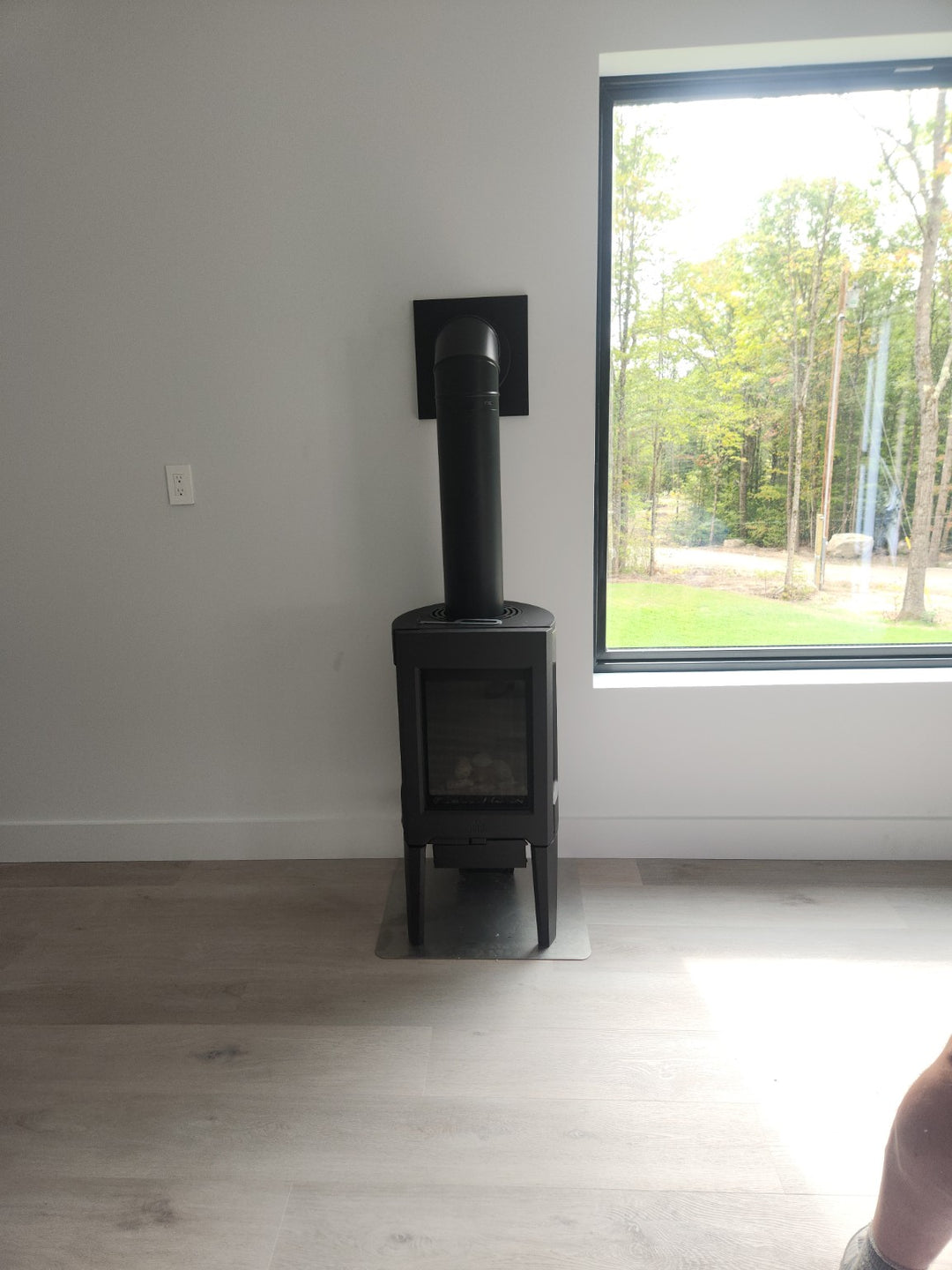 Contemporary freestanding stove installation by Hearth Doctor beside a large window