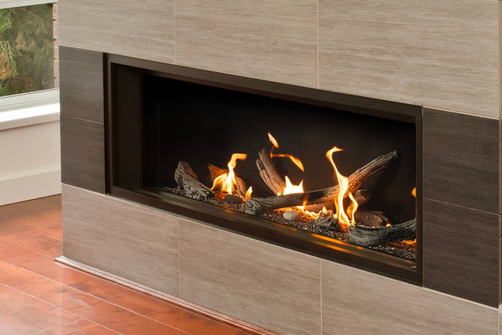 Valor L2 linear gas fireplace with driftwood logs and fluted black liner